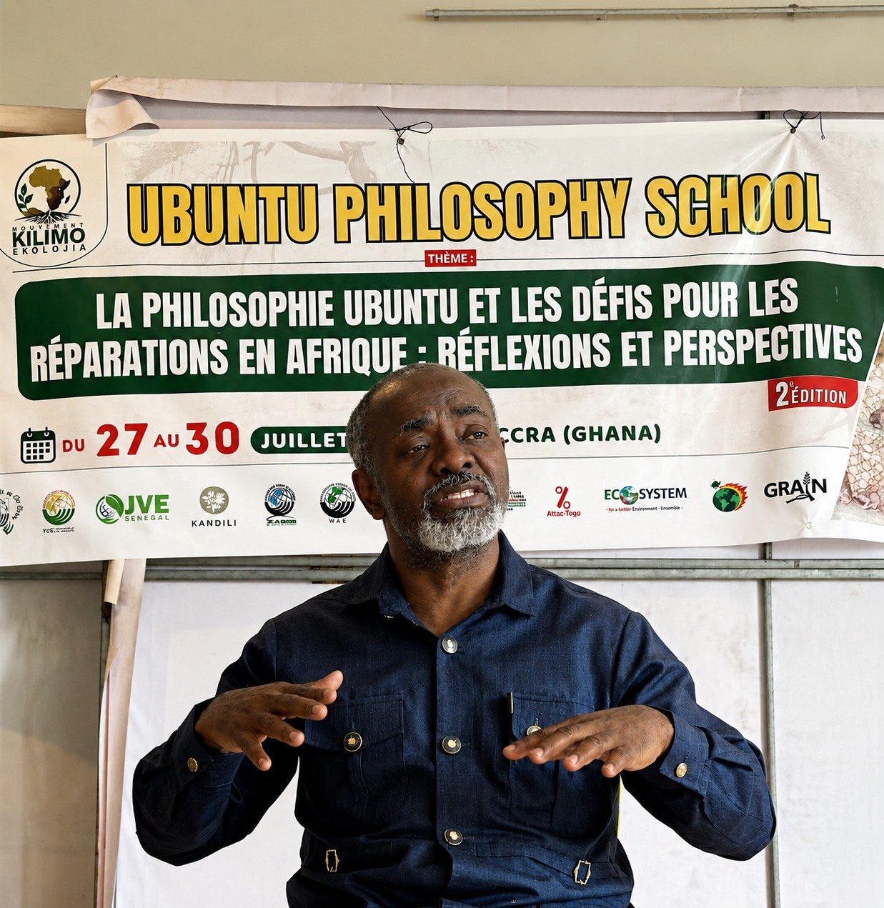 Dr. Gnaka Lagoke speaking in front of the Ubuntu Philosophy School banner