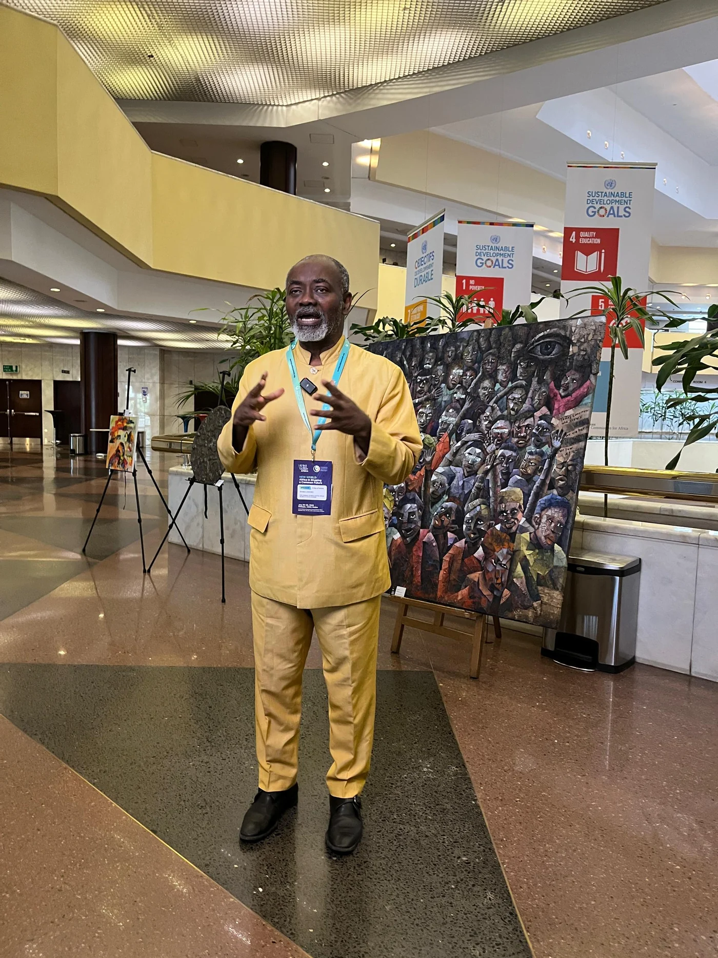 Dr. Gnaka Lagoke speaking beside sustainable development artwork